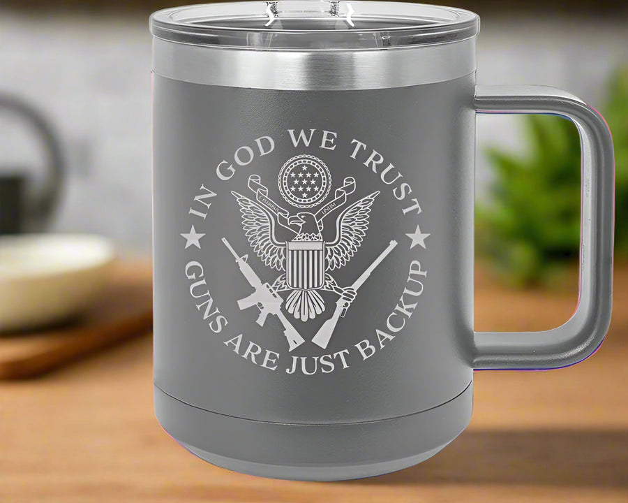 Gray insulated mug with 'In God We Trust' and 'Guns Are Just Backup' text 